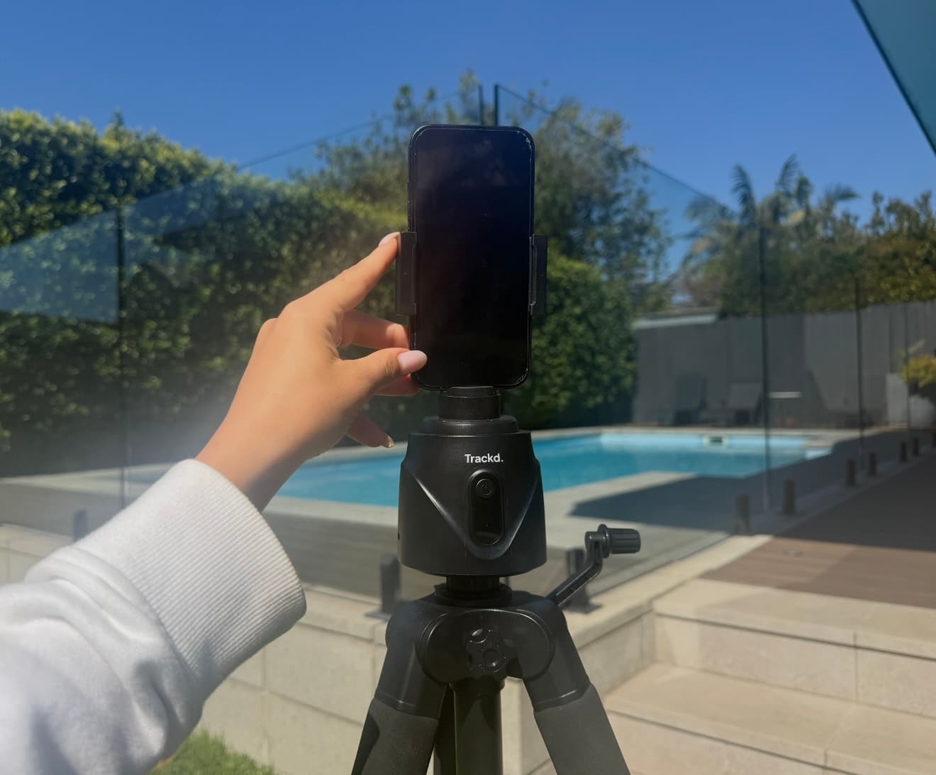 An iPhone being placed on a Trackd mount and tripod, ready to film